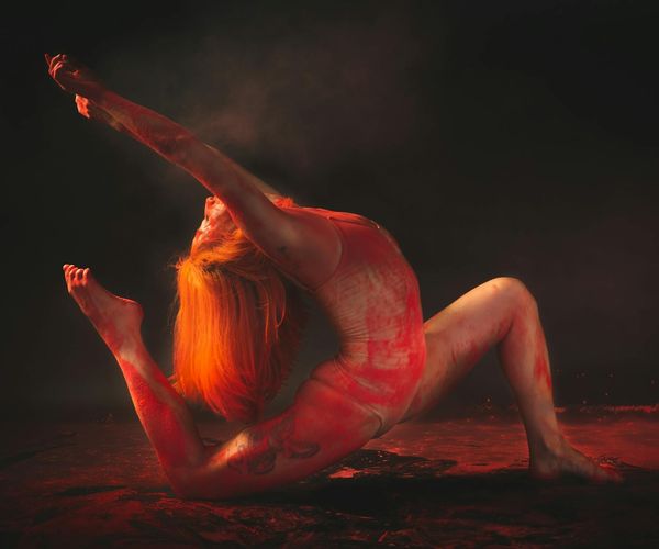 Person in a dynamic, flowing pose against a dark background.